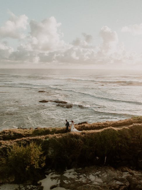 A couple walks hand in hand by the sea, capturing a serene and romantic moment at sunset.